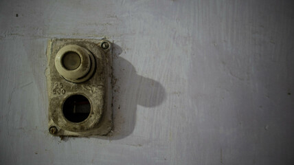 Close-up of an old, dusty vintage light switch on a textured wall, showing age and wear. Ideal for concepts related to history, vintage decor, or retro technology.