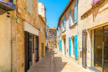 Obraz premium A picturesque narrow alley with bright blue shutters leading to the Fountain of Nostradamus in the medieval old town of Saint Remy, France, in the Provence Cote d'Azur.