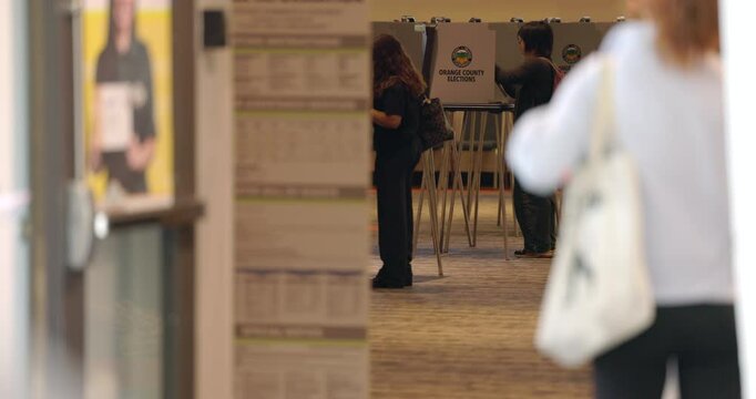 Fullerton, California, USA - November 5, 2024: Voters wait in line to vote in the 2024 presidential election behind a voting corruption warning sign.