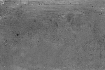Monochrome texture of a concrete wall with natural relief and damage in the form of chips and scratches. Fragment of an old stone surface with a crack. Dark rough surface with a place for an inscripti