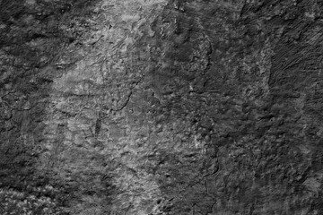 Monochrome texture of a concrete wall with natural relief and damage in the form of chips and scratches. Fragment of an old stone surface with a crack. Dark rough surface with a place for an inscripti