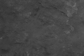 Monochrome texture of a concrete wall with natural relief and damage in the form of chips and scratches. Fragment of an old stone surface with a crack. Dark rough surface with a place for an inscripti