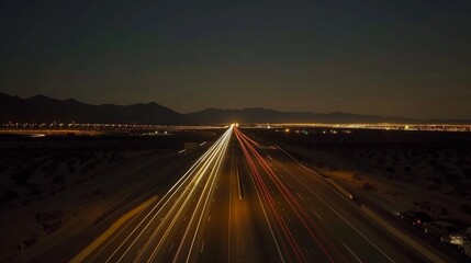 Obraz premium Amidst the vastness of the desert the steady flow of traffic on the highways is captured in the long straight light trails illuminating the darkness.