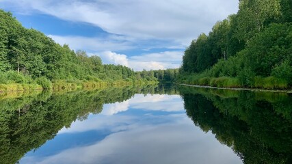 Obraz premium Serene River Mirror Reflecting a Blue Sky 