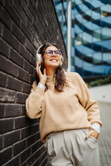 Fototapeta premium Young caucasian woman listening to music or audiobook outdoors 