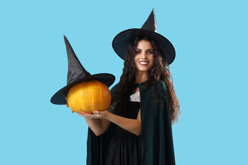 Young witch with Halloween pumpkin on blue background