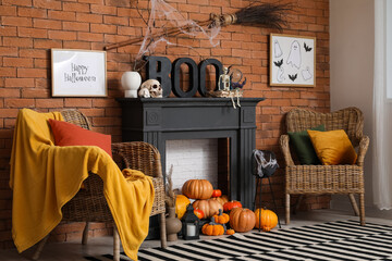 Fireplace with Halloween decorations, armchairs and pumpkins near brick wall