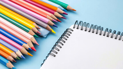 Charming arrangement of colorful pencils and blank spiral notebook, perfect for creative projects and artistic expression