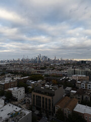 Naklejka premium Wide aerial view capturing the neighborhoods of Hoboken and Jersey City, with the iconic New York City skyline stretching across the horizon in the background. Overcast skies add depth 
