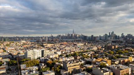Obraz premium Wide aerial view capturing the neighborhoods of Hoboken and Jersey City, with the iconic New York City skyline stretching across the horizon in the background. Overcast skies add depth 