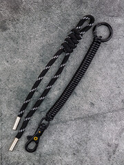 Close up of black rope keychain with knot and plastic spring on grey background
