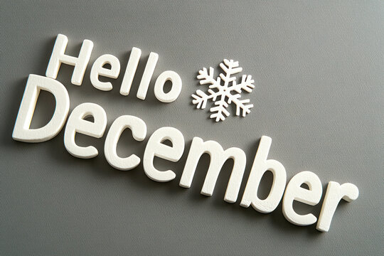 Hello December text with snowflake on gray background evokes winter vibes.