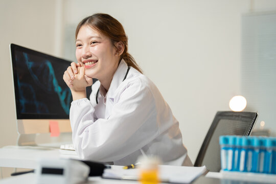 Young female doctor smiles while working on a computer in a medical lab with dna strands and blood samples, showing advances in genetic research