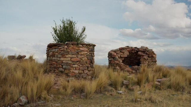 Inca chullpas in the Andes mountain range at sunset with a cloudy sky and surrounded by vegetation