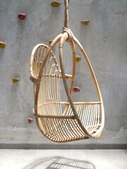 Industrial House Interior Showing Hanging Rattan Chair and Unfinished Wall With Colorful Climbing Points