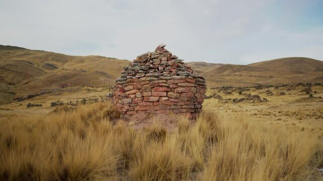 Inca chullpas in the Andes mountain range at sunset with a cloudy sky and surrounded by vegetation
