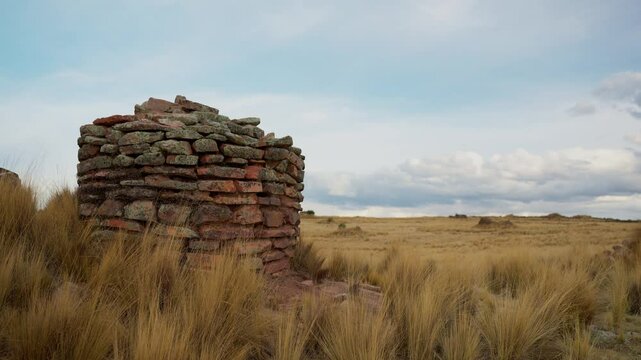 Inca chullpas in the Andes mountain range at sunset with a cloudy sky and surrounded by vegetation