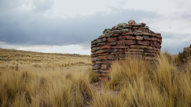 Inca chullpas in the Andes mountain range at sunset with a cloudy sky and surrounded by vegetation
