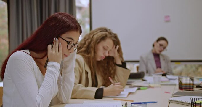 Focused students taking an exam in a classroom during classes, supervised by a professor. This stock video footage embodies education, concentration, and academic assessment.