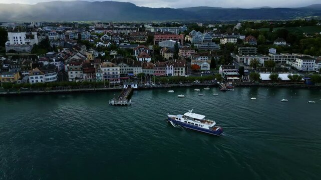 Orbit drone shot of boat arriving at Nyon pier on Lake Geneva in Switzerland