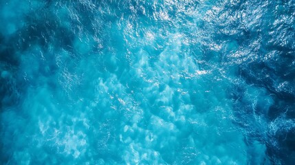 Obraz premium 77.A stunning overhead shot of crystal-clear blue water, the vibrant hues shifting from light aqua to deep blue. The surface is slightly disturbed by gentle waves, creating an enticing and