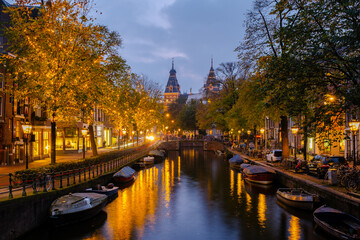 As twilight descends on Amsterdam, the canals reflect warm lights from trees and buildings. Boating...