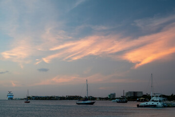 Naklejka premium a beautiful sunset in the port of Aruba with maritime vessels such as sailboats and a large cruise ship