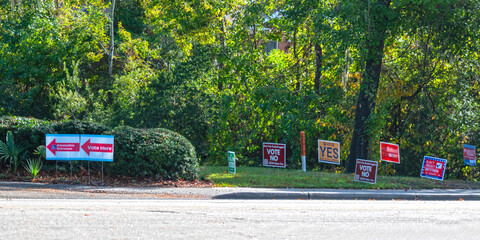 Vote Here signs directing voters to polling place with candidate signs to the right side.