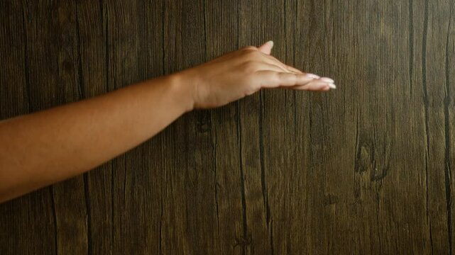 Woman's hand and fingers over a wood background showcasing a warm and natural setting with visible wood grains
