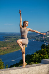 Fitness portrait young athletic woman doing gymnastics on blue sky background