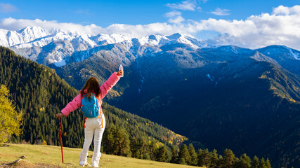Woman trekker with backpack and trekking poles on the hill enjoying the view in Mestia ,Georgia