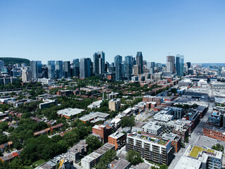 Aerial photograph of a modern city featuring a dense skyline of skyscrapers and a green residential area. Griffintown, Montreal, Quebec, Canada.