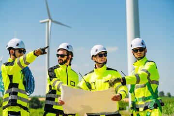 Fototapeta premium Four young male wind farm engineers work inspecting field systems.Wind turbine engineer inspection and wind turbine inspection progress at construction site.