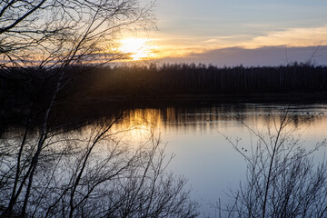 A breathtakingly beautiful sunset casting its warm golden light over a serene and peaceful lake with tree silhouettes