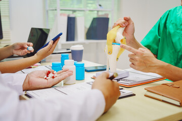 Three doctors sit together at a hospital desk, discussing bone health topics like osteoarthritis, osteoporosis, joint degeneration, ligament function, essential for skeletal structure and movement