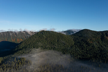 Beautiful aerial drone landscape with clouds over evergreen forests and mountains, captured early morning right after sunrise, in Mount Hood-Lost Lake territory, Oregon