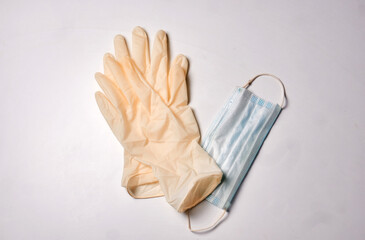 Pair of latex medical gloves and surgical mask with bow on white background. Protection concept
