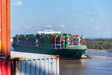 A massive cargo ship loaded with containers maneuvers carefully during docking operations at the...