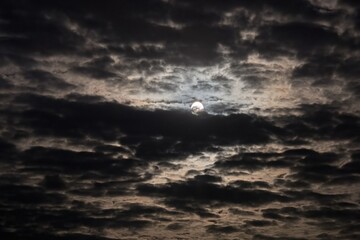 The full moon shines through the clouds.