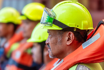 Crew members wear life jackets as they gather for an abandon ship drill, reviewing lifeboat...