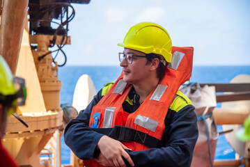 A ship's navigation officer stands ready during an abandon ship drill, focused and equipped, embodying the discipline and vigilance essential to maritime safety.