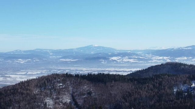 Panoramic view of Babia Gora peak covered in snow with surrounding mountain scenery in the Beskidy Mountains, Poland.