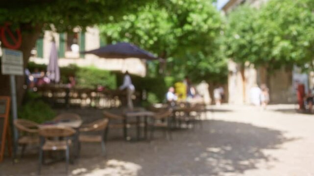 Blurred outdoor scene in mallorca featuring people dining under umbrellas with a defocused background and bokeh effect on a sunny day