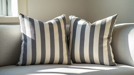 Two gray and white striped throw pillows on a white couch.