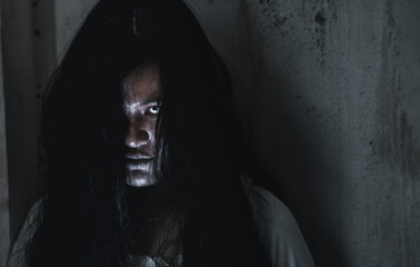 Scary ghost woman. Portrait of Asian ghost or zombie horror creepy scary have hair covering the face her eye at abandoned house dark tone, female make up zombie face, Happy Halloween day concept