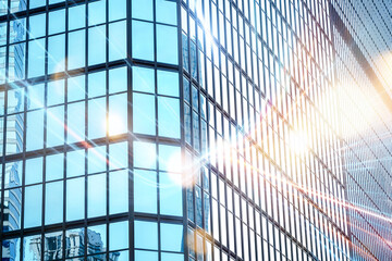 A modern skyscraper with a glass facade reflects the sun and a bright city skyline.