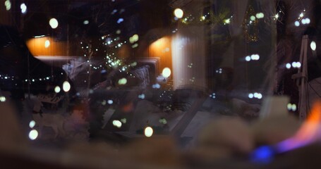 Soft glow of biofire and festive bokeh lights create dreamy, magical ambiance. Reflections blend...