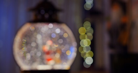 Out of focus Santa and reindeer in snow globe recreate classic winter fairy tale. Sparkling snowflakes festive decorations add touch of magic holiday wonder to surroundings. Blur of lights, snowflakes