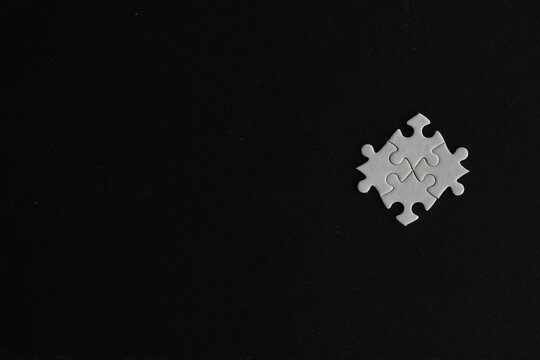 White Jigsaw Puzzle Pieces on Black Background Representing Problem Solving and Minimalism
