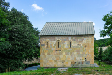 Obraz premium Church of the Holy Trinity near the town of Kazreti. Light stone walls, a beautiful garden with trees and flowers